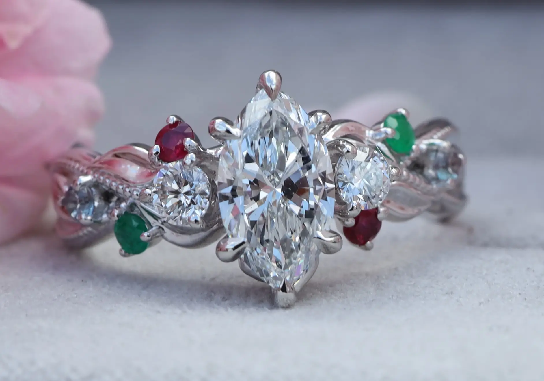 custom marquise diamond engagement ring with twist band and ruby and emerald accent stones